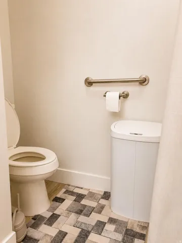 Neutral wall paint, rectangular tiled flooring, and a brushed nickel grab bar