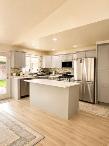 Kitchen featuring a central island with countertop, light wood-finish flooring, stainless steel appliances, and grey cabinetry