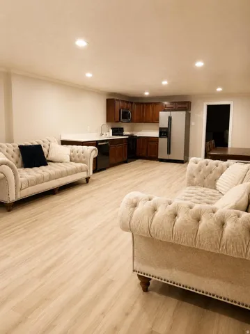 Recessed lighting, wood-finish flooring, kitchen area with wood cabinetry, light-toned countertops, and stainless steel appliances