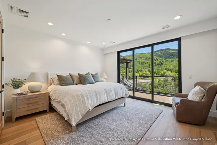 Expansive sliding glass doors, recessed ceiling lighting, wood-finish flooring, and a private balcony with railing