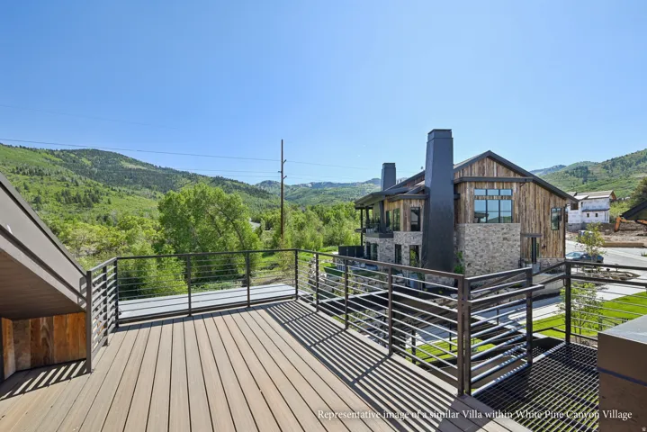 Expansive outdoor deck with wood-finish flooring and metal railings, showcasing mountain scenery