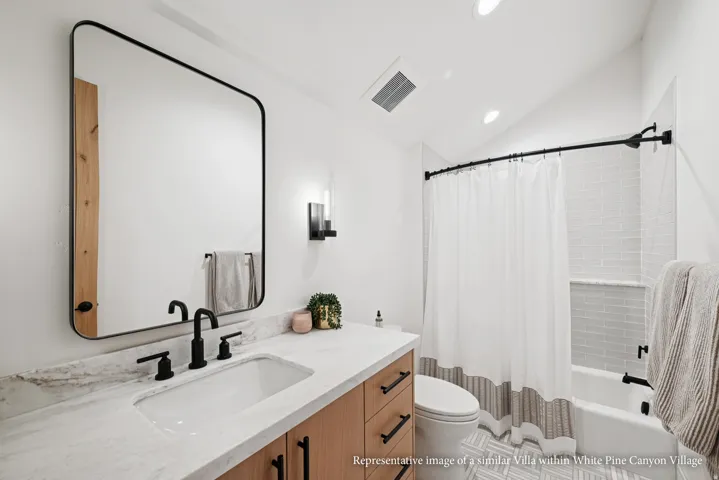 White vanity with integrated sink, black fixtures, and a large wall-mounted mirror