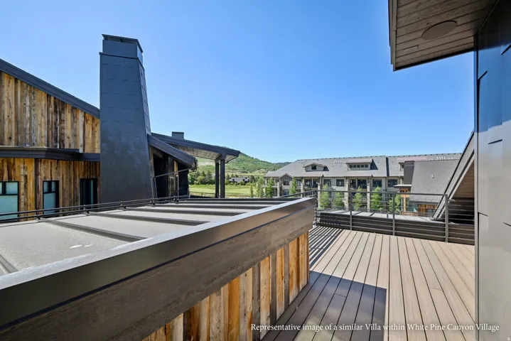 Expansive outdoor deck with composite decking, modern glass railings, and a prominent metal-clad chimney