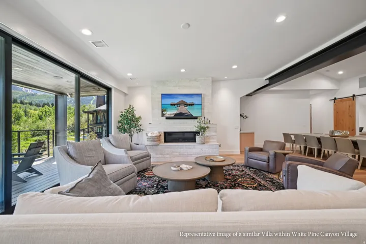 Spacious living area featuring a stone-clad fireplace, recessed lighting, and wood-finish flooring