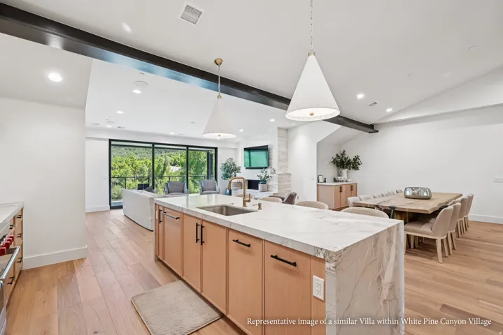Open-concept living area with wood-finish flooring, a kitchen island with stone countertop, recessed lighting, and large sliding glass doors