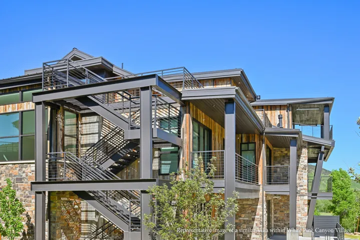 Multi-level exterior featuring a stone and wood-finish facade, exposed structural beams, multiple balconies with horizontal railing, and an external staircase