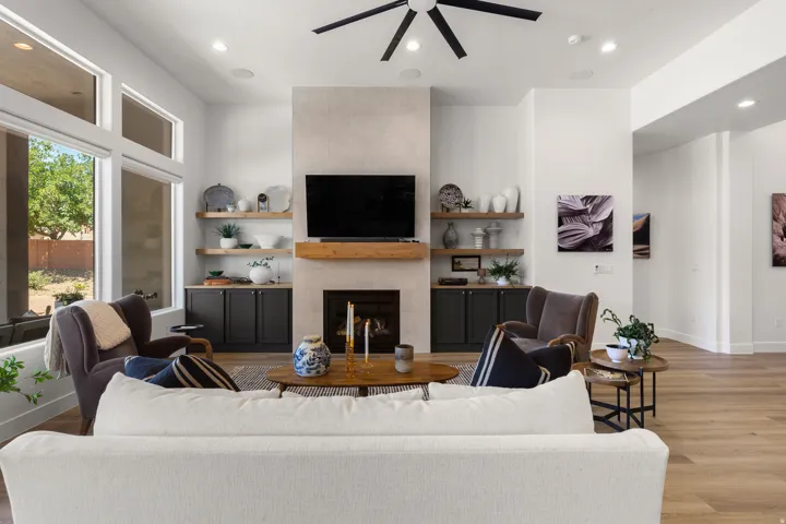 Spacious living area featuring a central fireplace with an integrated hearth, flanked by built-in cabinetry and floating wood shelves
