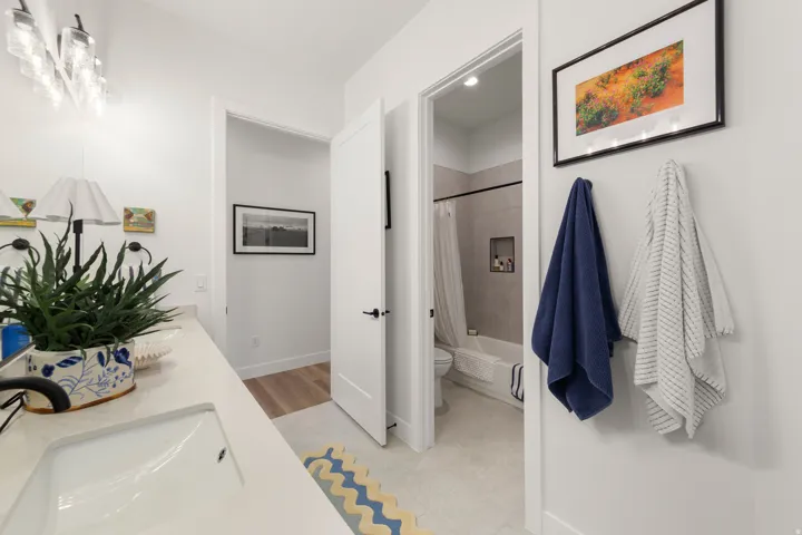 White bathroom vanity with an integrated sink, modern lighting fixture, and light-toned wall paint