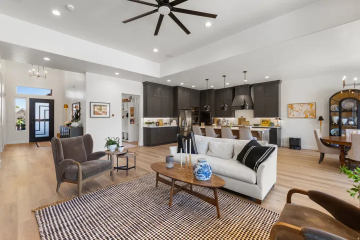 Open-concept living space featuring wood-finish flooring, recessed lighting, and a dark-toned kitchen with pendant lighting