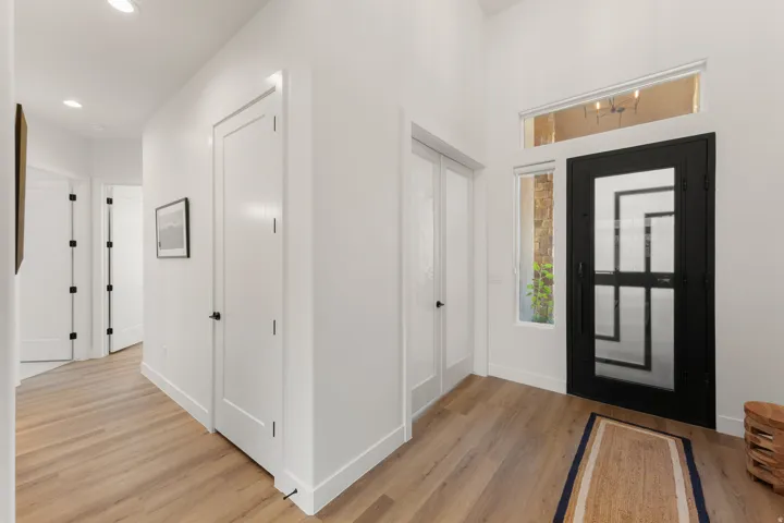 Wood-finish flooring, recessed lighting, white walls, and a black front door with multiple glass panes and sidelight