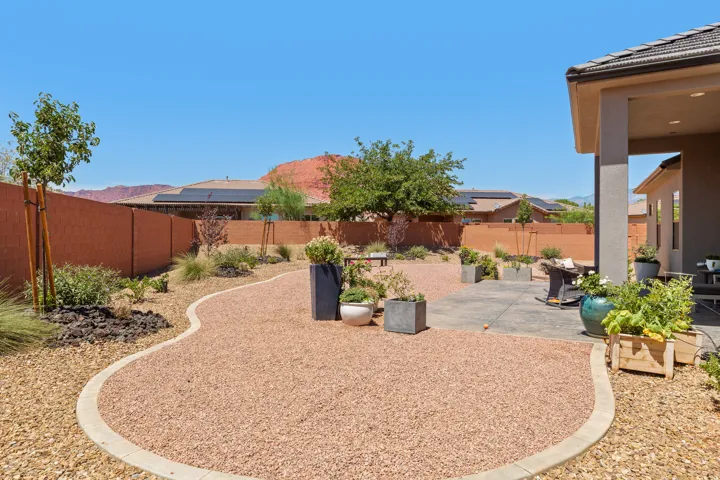 Expansive backyard featuring a concrete patio, gravel pathways, and planted beds