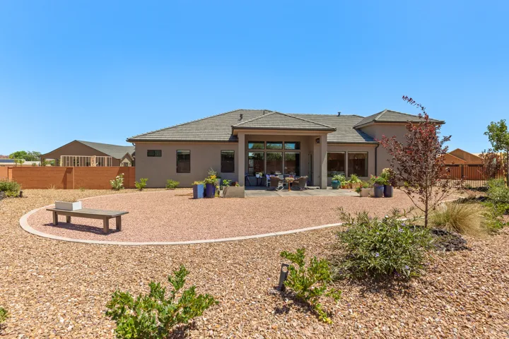 Expansive backyard featuring a large patio, stucco exterior, multiple large windows, and a tiled roof