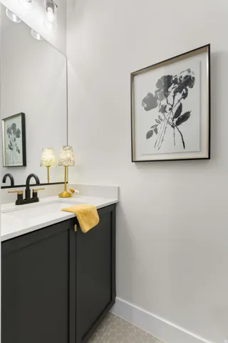 Floating vanity with dark cabinetry, white countertop, and black faucet