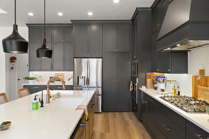 Dark-stained cabinetry, stainless steel appliances, wood-finish flooring, recessed lighting, and a kitchen island with an integrated sink