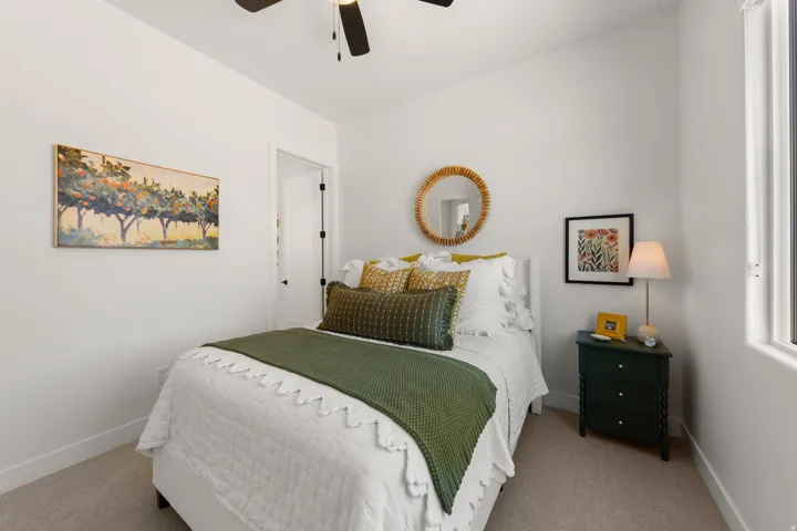 Neutral wall paint, carpeted flooring, window with white trim, white door with black hardware, and a ceiling fan with integrated lighting