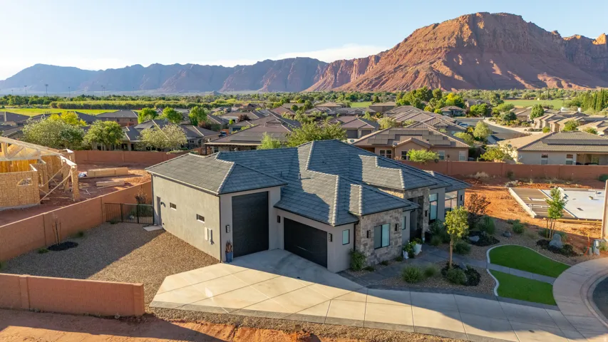 Contemporary home featuring a stone facade, a multi-car garage, an integrated driveway, and a landscaped front yard with a curved pathway
