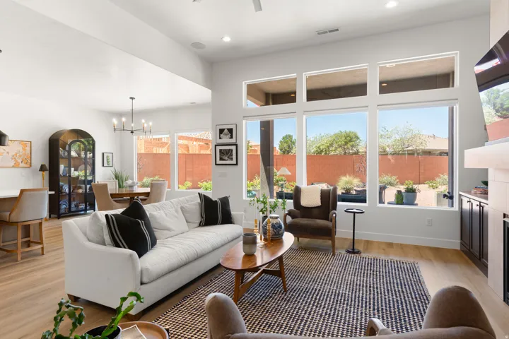 Expansive living area featuring wood-finish flooring, high ceilings, large windows, and a built-in fireplace with cabinetry