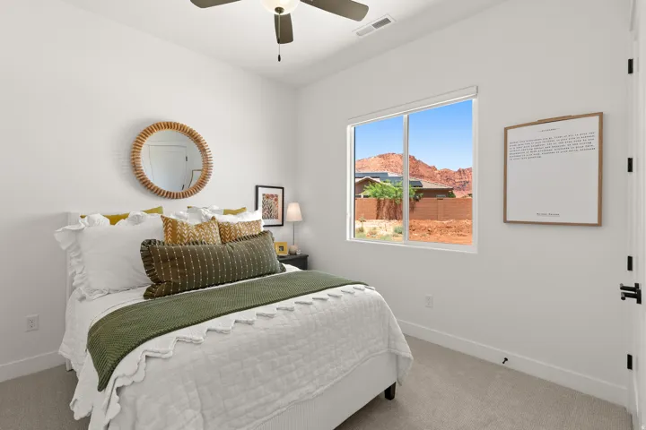 Window with desert mountain scenery, ceiling fan, white walls, and gray carpet