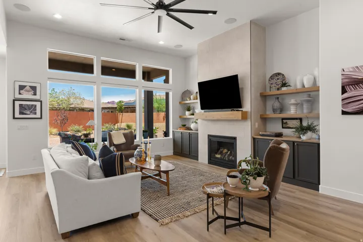 Contemporary living area with wood-finish flooring, a linear electric fireplace with a wood mantel, and built-in cabinetry with open shelving