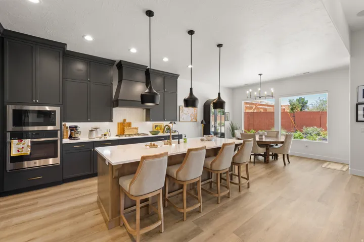 Modern kitchen with dark cabinetry, stainless steel appliances, a center island with seating, and wood-finish flooring