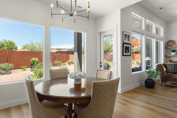 Expansive window array, contemporary chandelier, wood-finish flooring, and a glass-paneled exterior door