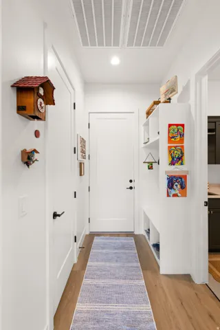 Wood-finish flooring, white built-in shelving, white paneled doors, and contemporary black hardware