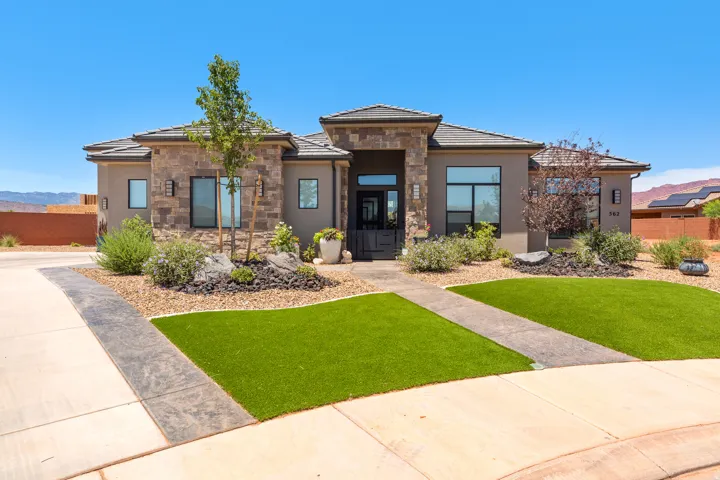 Stone and stucco exterior with a tile roof, featuring a distinct entryway and a landscaped front yard with artificial turf and decorative rock