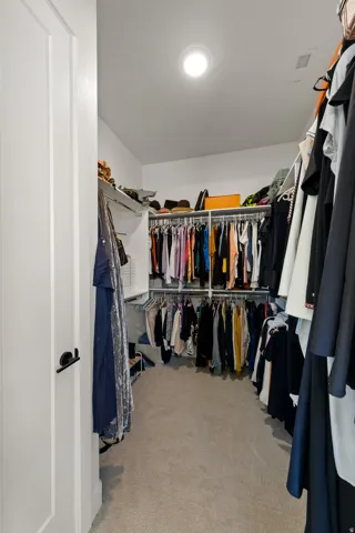 Walk-in closet featuring carpet flooring, built-in shelving, and recessed lighting