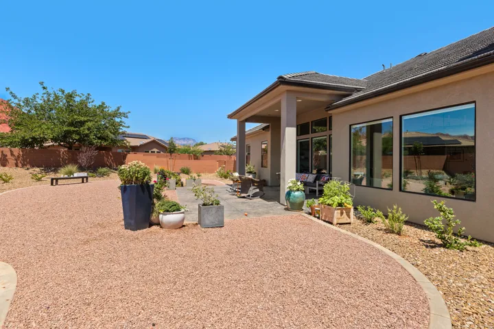 Exterior with a covered patio, paved hardscaping, large windows, and a gravel-finished yard