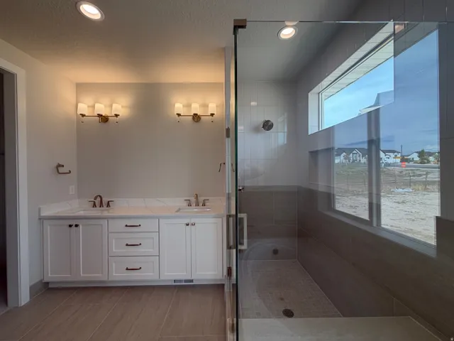 Double vanity with white cabinetry, dual sinks, and wall-mounted light fixtures