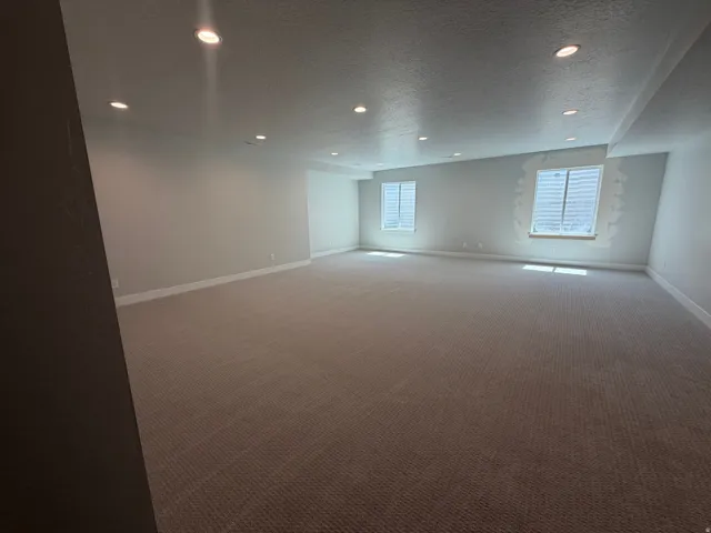 Expansive room featuring recessed lighting, a neutral color palette, and two casement windows with privacy blinds