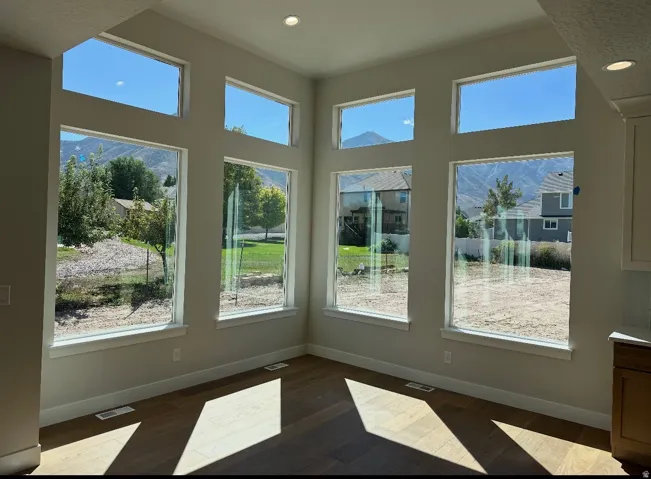 Expansive window wall with multiple large windows, wood-finish flooring, and recessed ceiling lighting