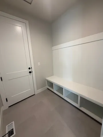Built-in bench seating with cubby storage, modern two-panel door with black hardware, and light wood-finish flooring