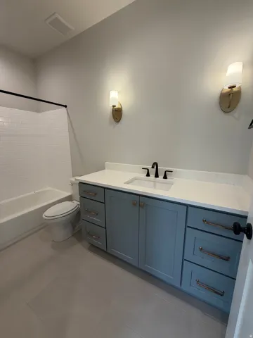 Bathroom featuring a white subway tile tub surround, sleek white bathtub, and a light blue vanity with a white countertop
