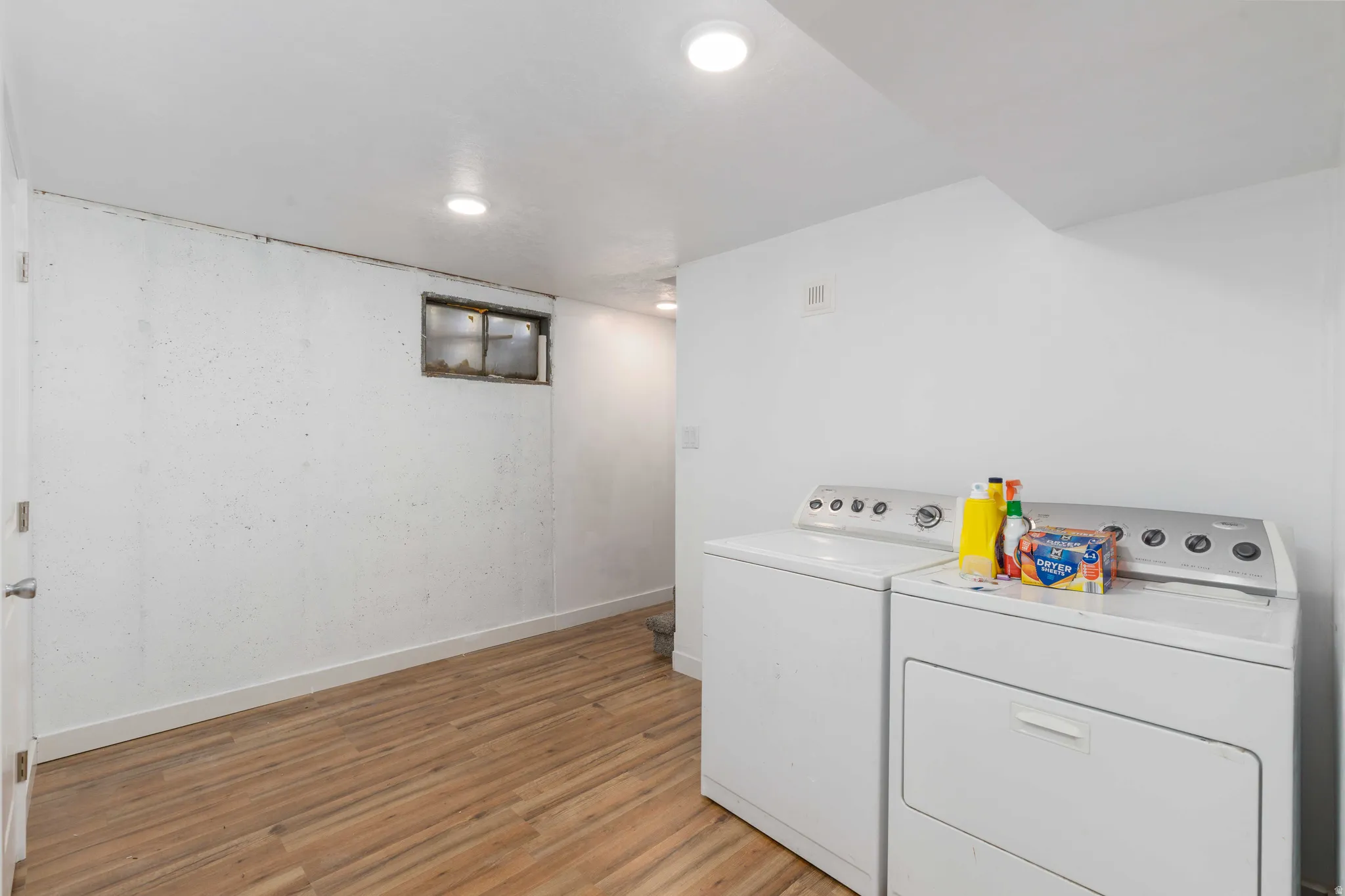 Laundry area featuring wood-finish flooring, recessed lighting, and a window