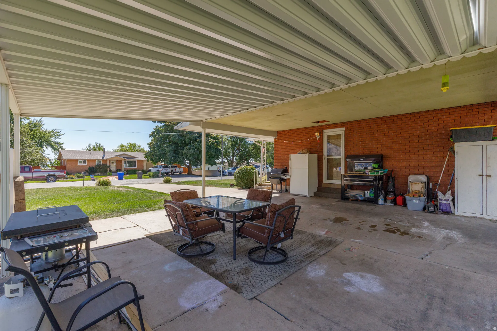 Expansive covered patio with concrete flooring, brick exterior wall, and direct outdoor access