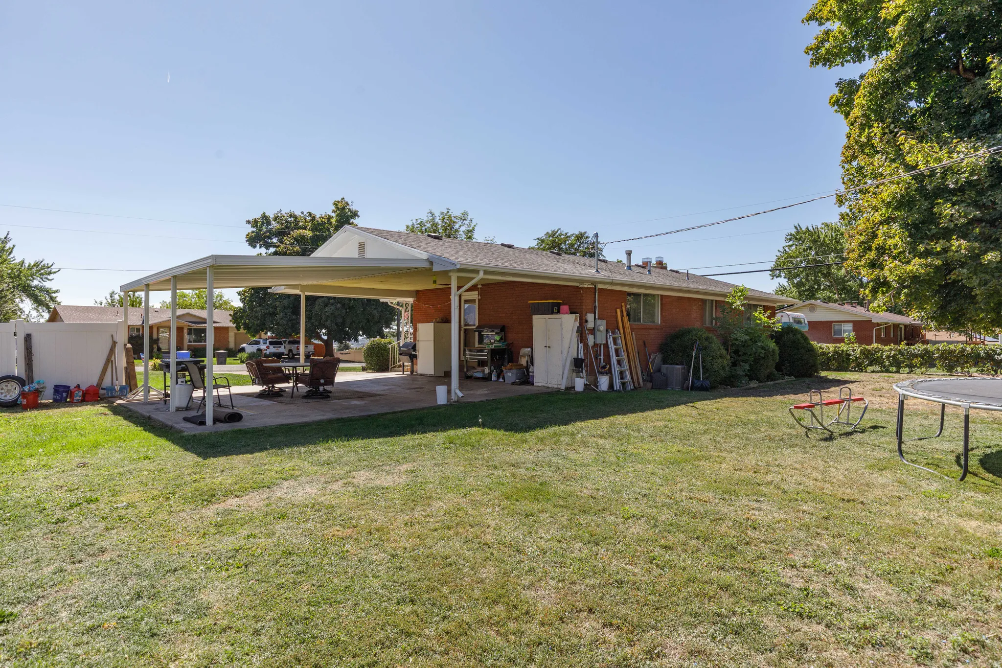 Expansive lawn area with a covered patio and brick exterior