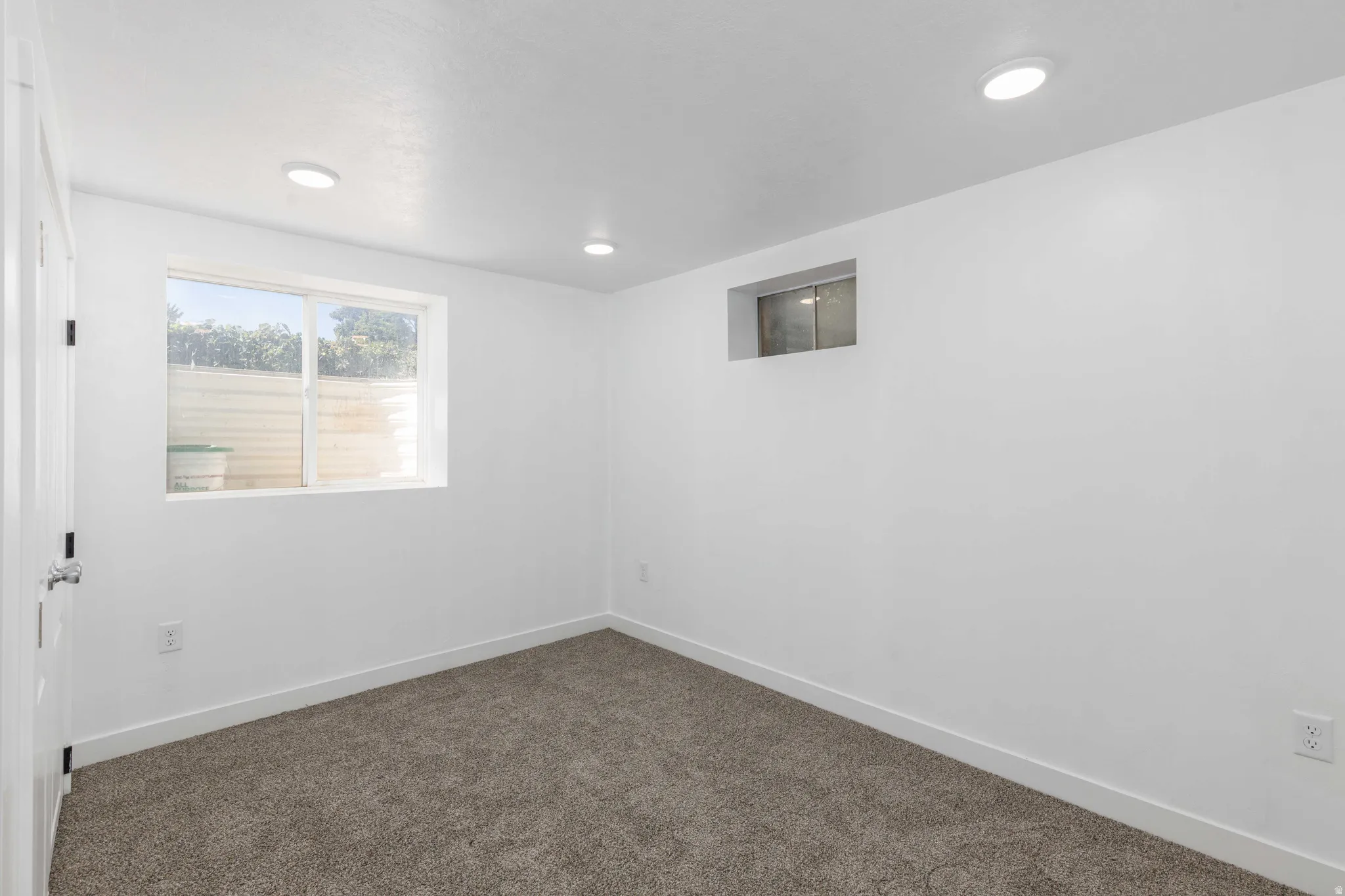 Recessed ceiling lighting, white walls, and gray carpet flooring