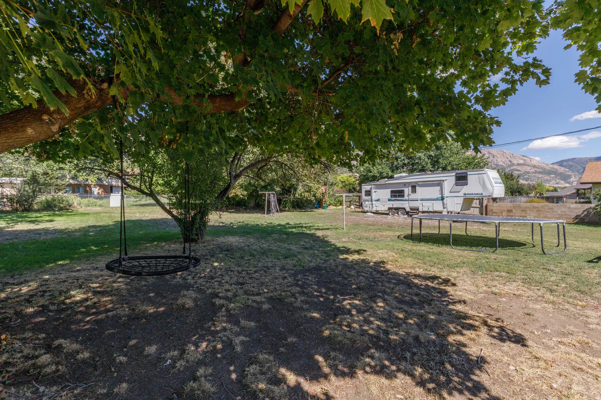 Expansive backyard with mature trees providing shade and a natural landscape