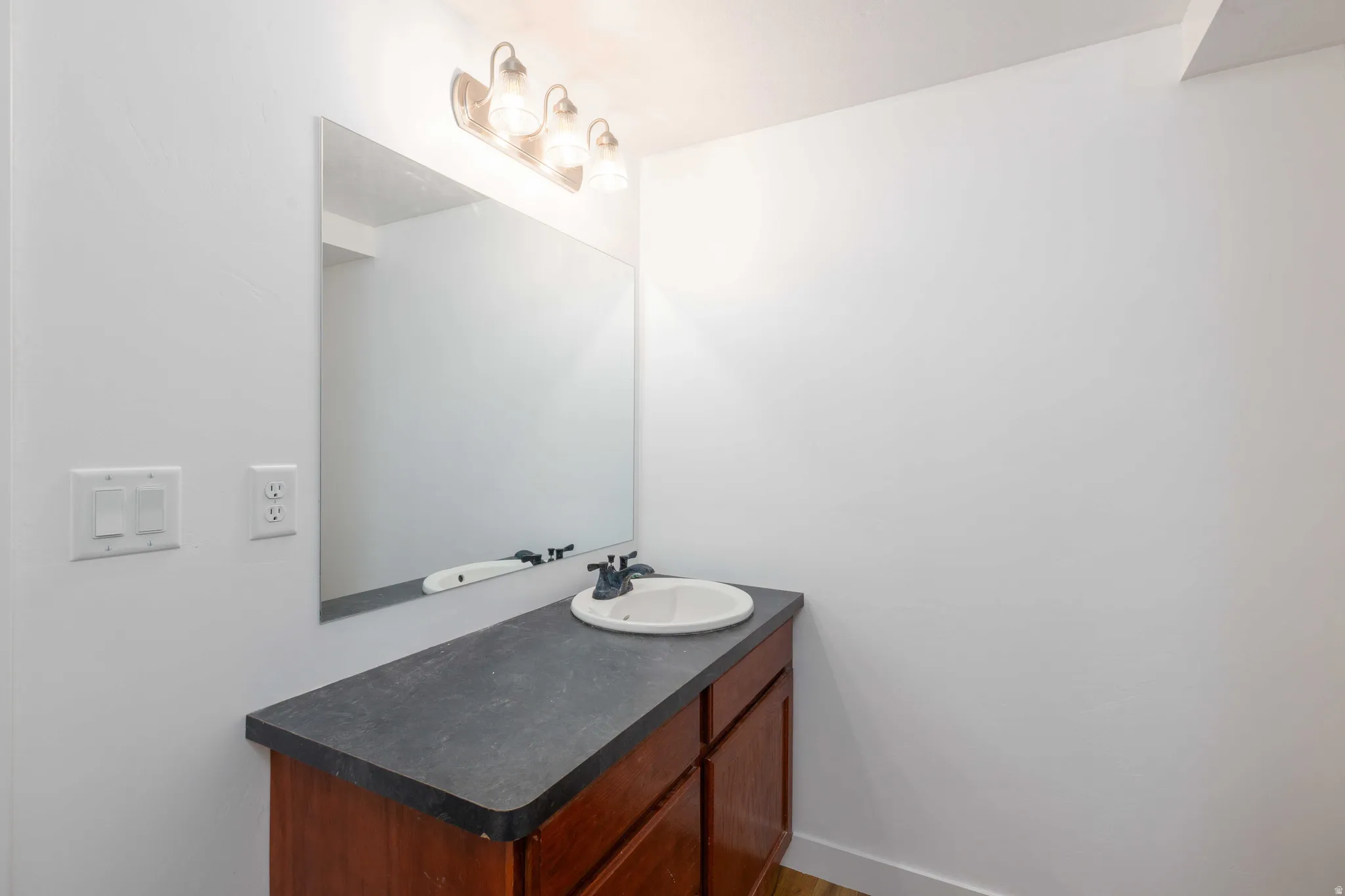 Vanity with wood-finish cabinetry, countertop, and integrated sink