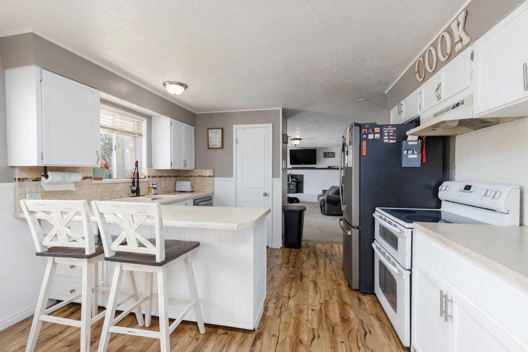 Kitchen featuring wood-finish flooring, white cabinetry, a built-in kitchen island, and a tile backsplash