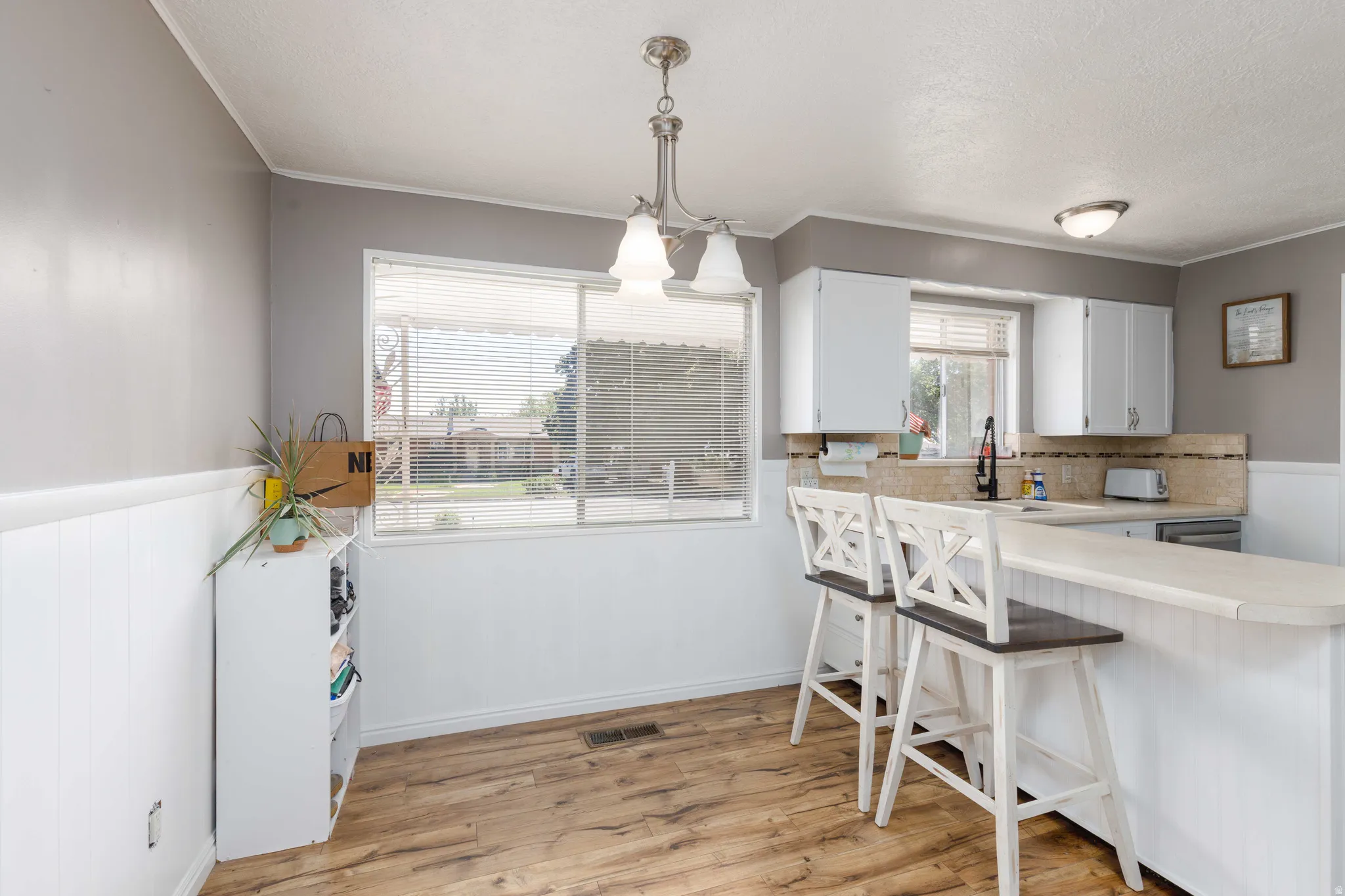 Kitchen area featuring wood-finish flooring, white cabinetry, a built-in breakfast bar, a window, and recessed lighting
