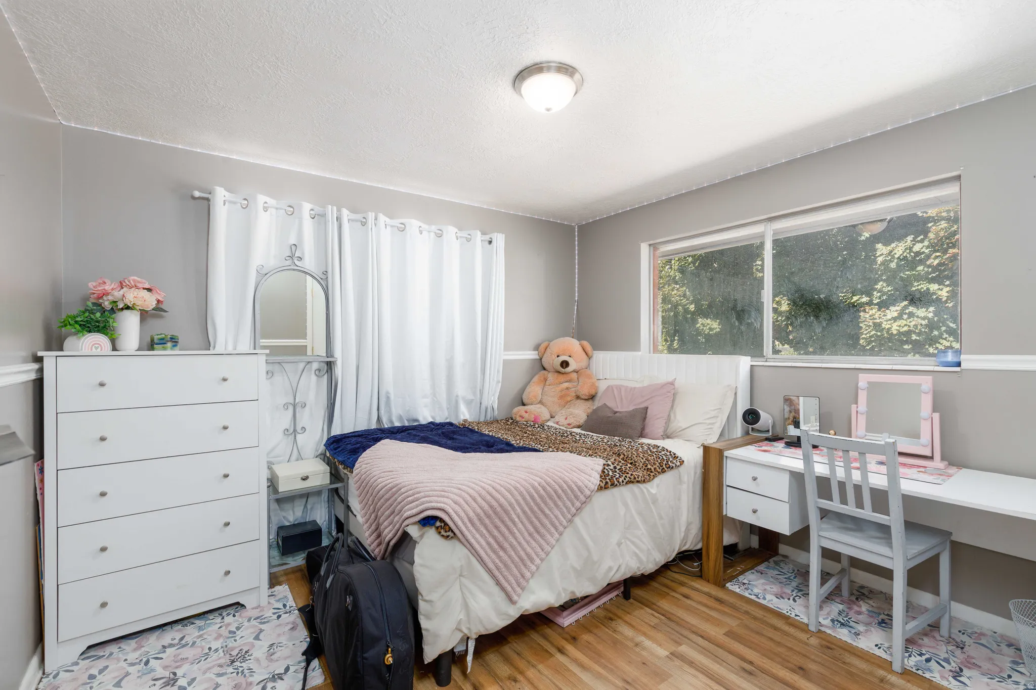 Wood-finish flooring, neutral wall tones with chair rail molding, and a large window with white trim