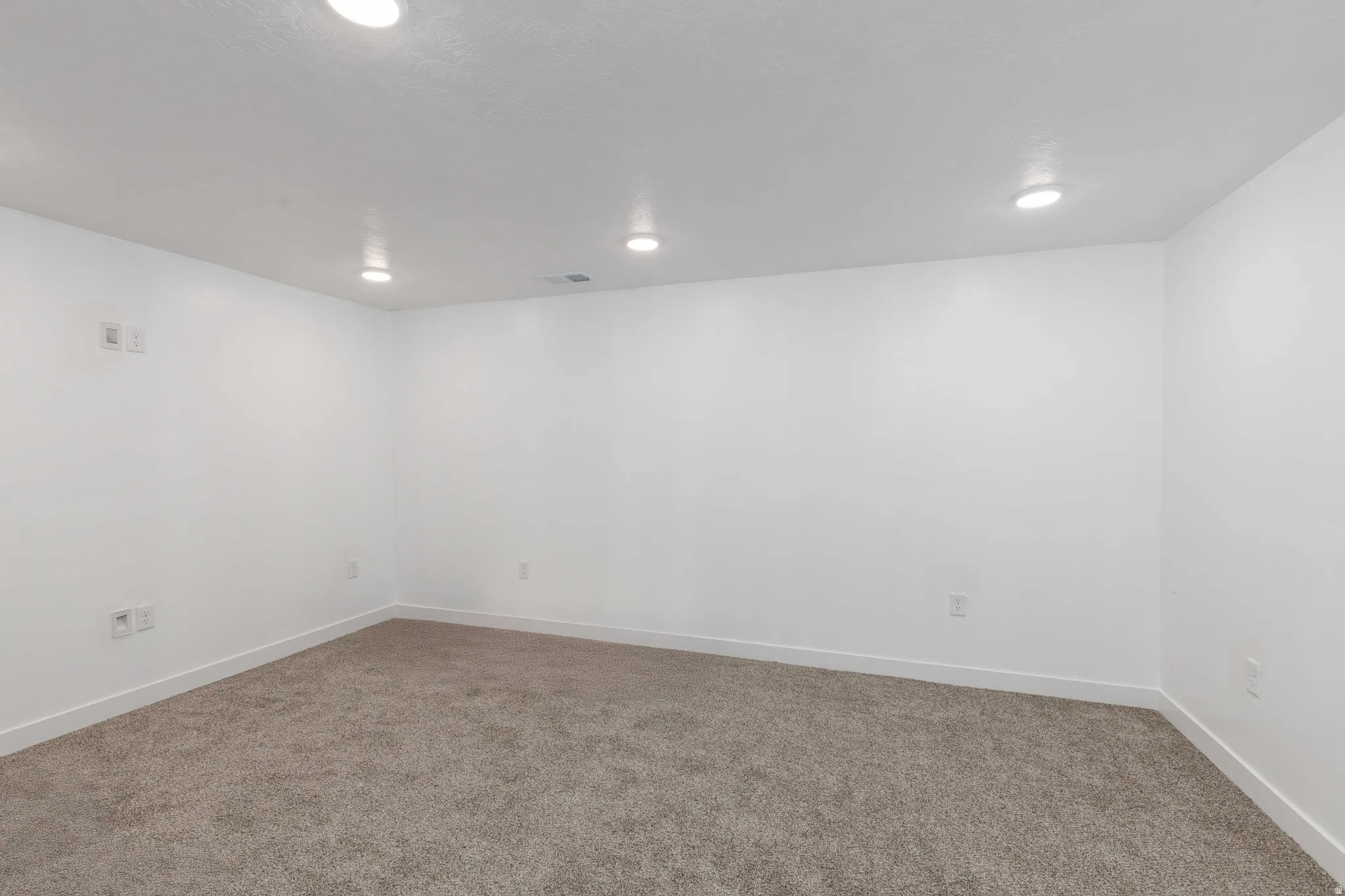 Recessed lighting illuminates neutral walls and carpeting