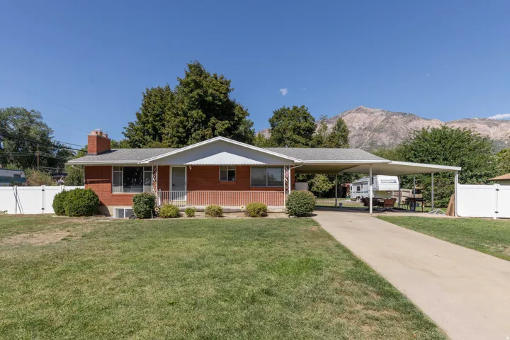 Brick exterior with a covered carport, front porch, and a gravel driveway