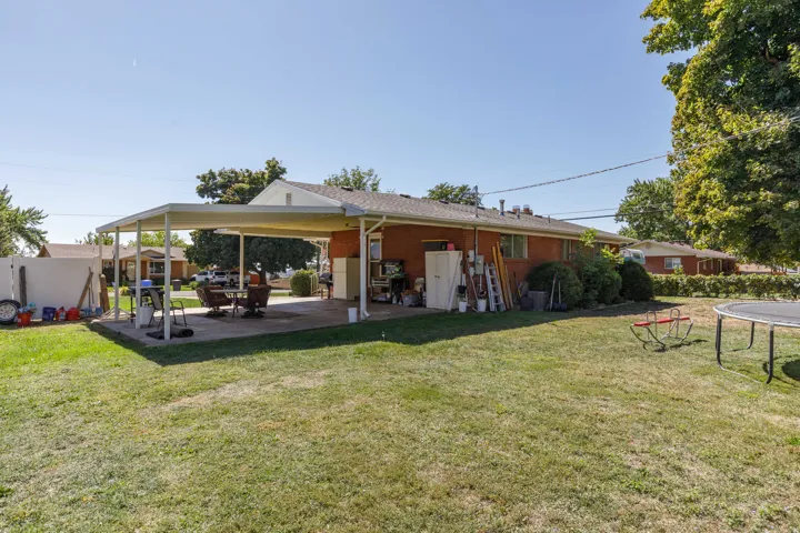 Expansive lawn area with a covered patio and brick exterior