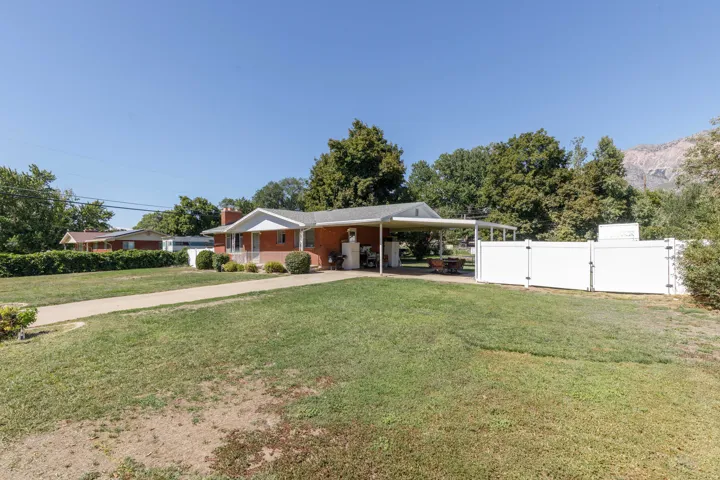 Brick exterior with white trim, covered carport, front porch, and a white privacy fence