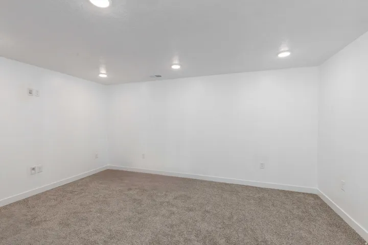 Recessed lighting illuminates neutral walls and carpeting