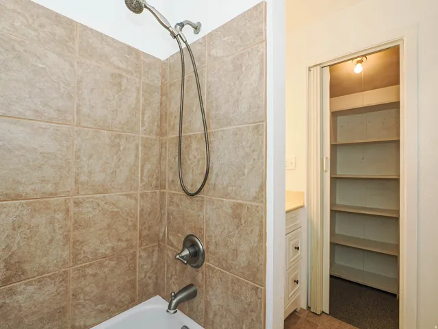 Bathtub and shower combination with tile surround, brushed nickel fixtures, and a handheld showerhead