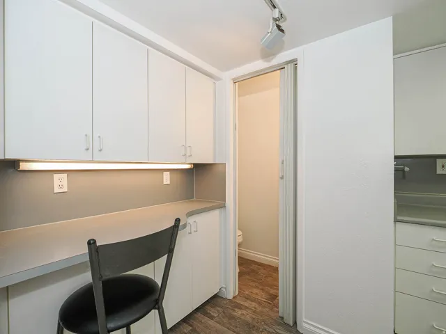 Built-in desk with overhead and under-cabinet storage, track lighting, and wood-finish flooring